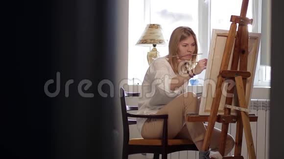 坐在靠窗的椅子上画画的小女孩视频的预览图