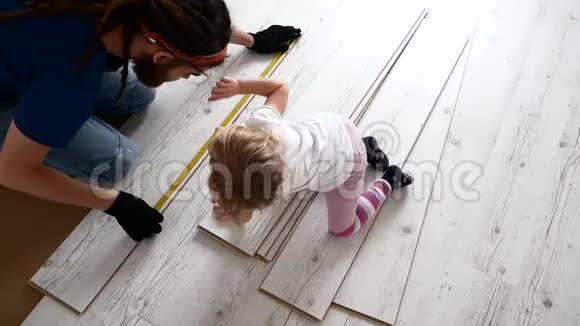 爸爸和女儿正在公寓里修理层压板铺设视频的预览图