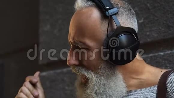 留胡子的人带着耳机在户外唱歌视频的预览图