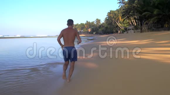 肌肉体操运动员沿着黄沙缓慢的背面奔跑视频的预览图