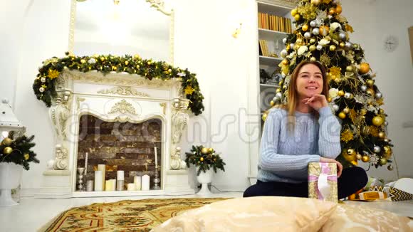 节日前夕迷人的女性可爱的微笑带着礼物摆姿势坐在客厅的地板上背景是视频的预览图