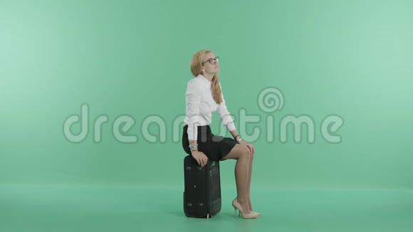 一个戴眼镜的女人坐在行李上视频的预览图
