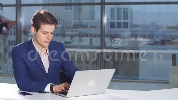 年轻有魅力的商人在办公桌上工作的肖像在办公室里使用笔记本电脑视频的预览图