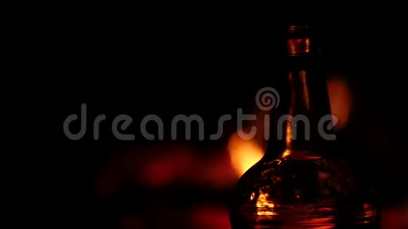 啤酒瓶在黑暗中的火背景上棕色玻璃上的火焰游戏慢动作视频的预览图