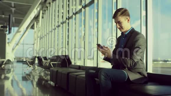 年轻的商人正在机场谈论他的智能手机视频的预览图