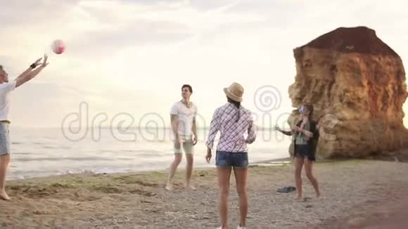 快乐的年轻朋友晚上在海边的海滩上玩排球活跃的假期慢镜头视频的预览图