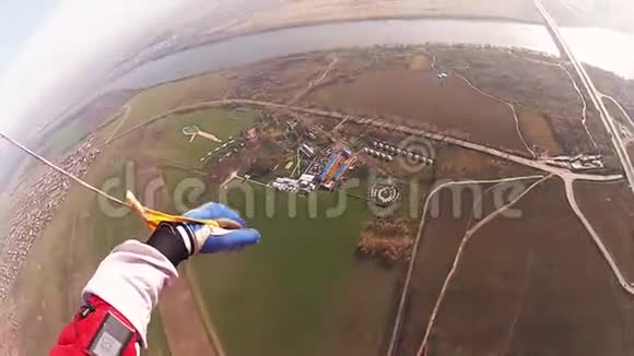 跳伞员跳伞在多云的天空上绿色的田野身高景观太阳视频的预览图