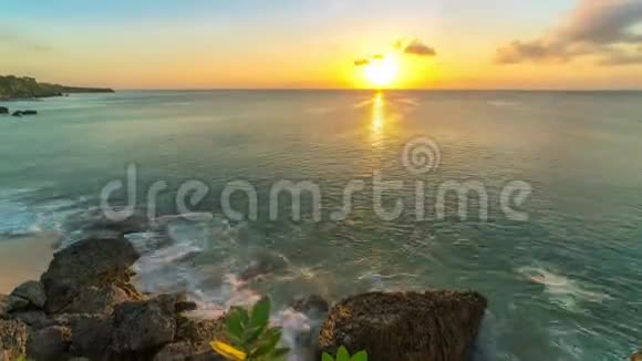 印度尼西亚巴厘岛海滩上日落时间的推移底部的海浪拍打着岩石视频的预览图