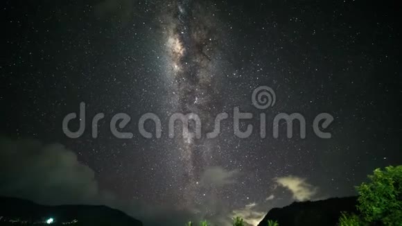 夜晚的风景随着五颜六色的银河和多云的光线在山上流逝带热带山脉的星空视频的预览图