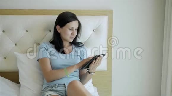 清晨躺在床上使用平板电脑的少女视频的预览图