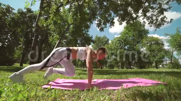 在公园户外做俯卧撑运动和训练的美丽苗条运动女子的侧景视频的预览图