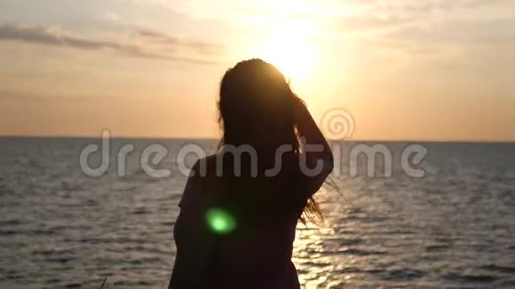 一个女孩站在海滩上在日落时眺望远处4K3840x2160高清高清视频的预览图