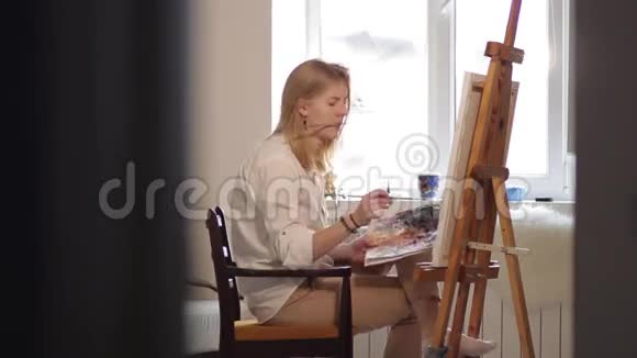 女艺术家画水彩画触摸她的头发视频的预览图