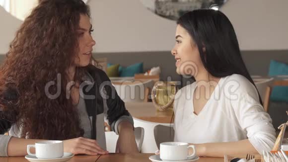两个女孩在咖啡馆里做心脏手势视频的预览图