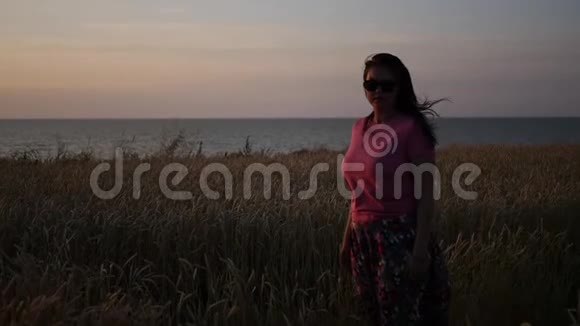一个女孩站在靠近大海的麦田里挥动着她的手高清1920x1080慢动作视频的预览图