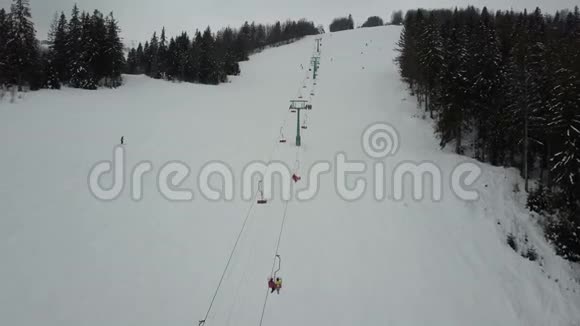 乘坐喀尔巴阡山滑雪缆车空中俯瞰人们在滑雪板上下降视频的预览图