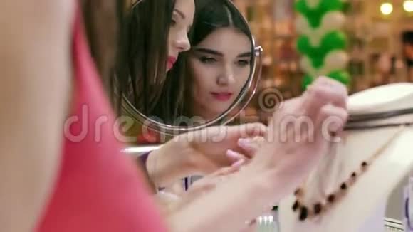 两名年轻的购物妇女在镜子中的特写镜头视频的预览图