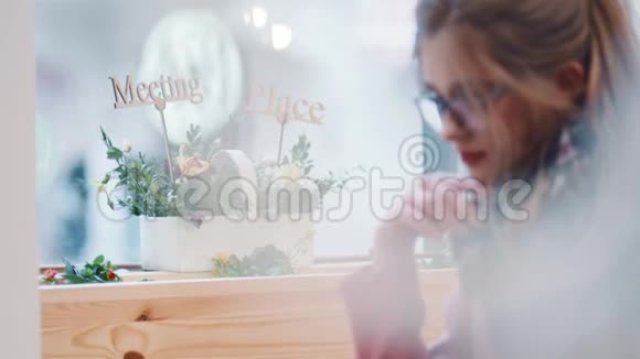 一位穿着休闲服的年轻漂亮女士模糊地看着拿着平板电脑在咖啡馆A放松然后接电话视频的预览图