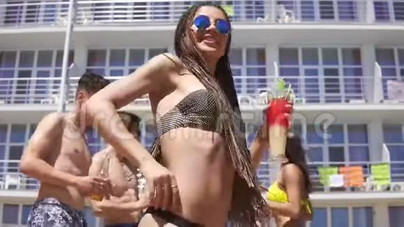 年轻漂亮的女孩带着恐惧和太阳镜在泳池派对上跳舞时她会坐在摄像机前快乐的朋友视频的预览图