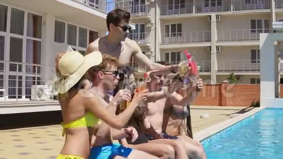 快乐的一群年轻的朋友在夏天的时候在泳池边玩着玩着玩干杯视频的预览图