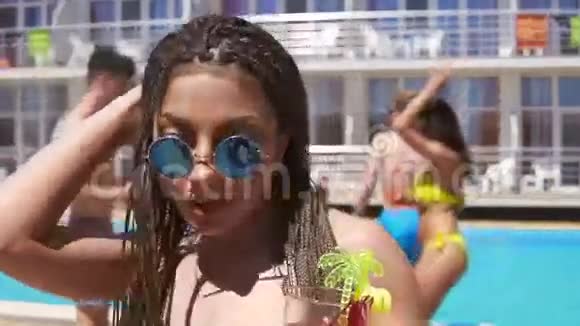 年轻漂亮的女孩带着恐惧和太阳镜在泳池派对上跳舞时她会坐在摄像机前夏季视频的预览图