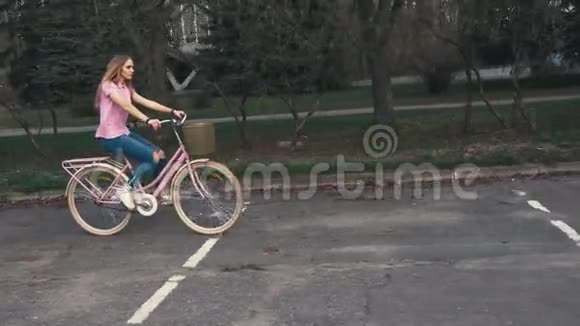 夏天的城市公园里一个红发女孩骑着一辆带篮子的自行车视频的预览图