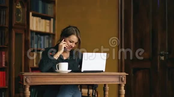 一个年轻漂亮的女学生在室内图书馆学习时用手机说话视频的预览图