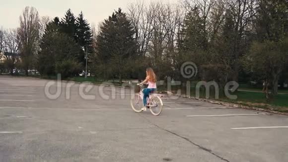夏天的城市公园里一个红发女孩骑着一辆带篮子的自行车视频的预览图