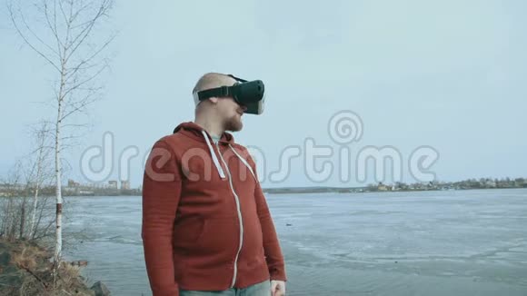 一个人站在一个春天的池塘旁边用虚拟现实眼镜视频的预览图