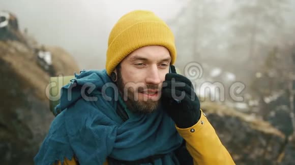 有胡子的人穿着黄色的冬衣在电话里说话一个徒步旅行者带着背包去冬山视频的预览图