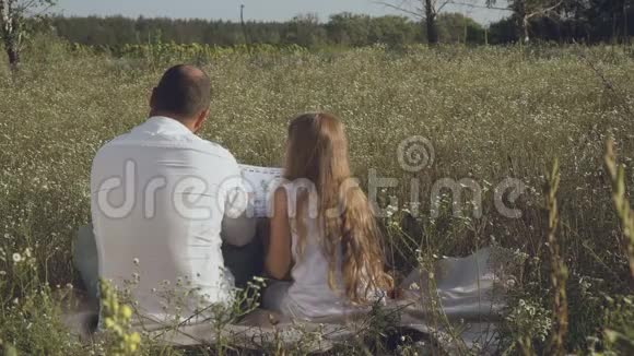 男人和小女孩在草地上看书视频的预览图