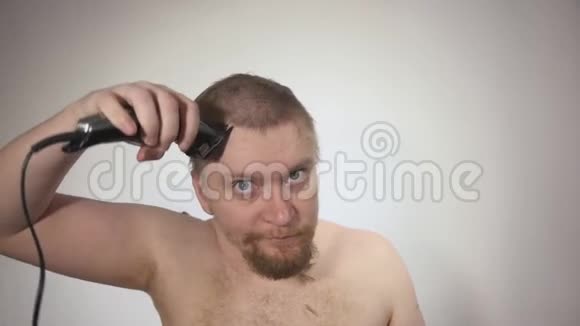 男人用剪刀在白色背景上剃光头拍摄特写镜头视频的预览图