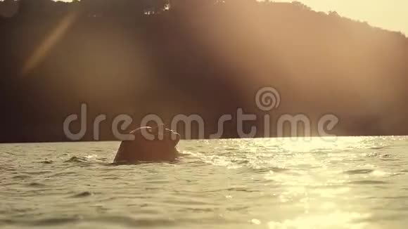 年轻性感的美女在美丽的金色夕阳下在海里游泳慢动作1920x1080视频的预览图