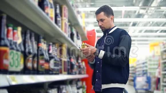 在超市里挑选一罐啤酒的人视频的预览图
