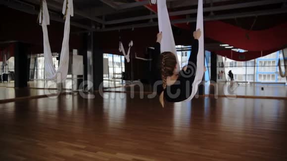 在空中瑜伽工作室里女人用吊床翻着头视频的预览图