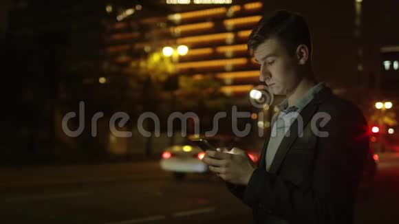 年轻的游客晚上站在街上发短信视频的预览图