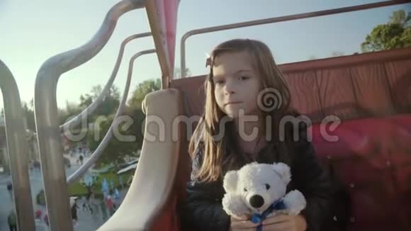 可爱快乐的小女孩带着泰迪熊在旋转木马上视频的预览图