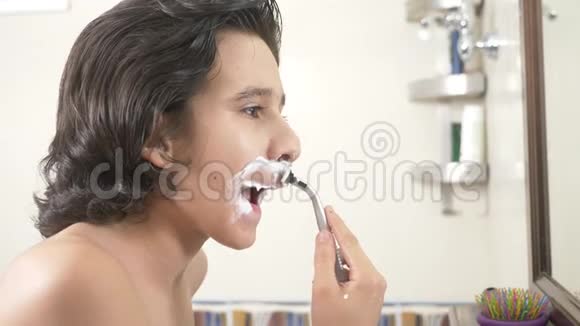 青少年第一次刮胡子十几岁的男孩用剃须泡沫护肤品奶油脸视频的预览图