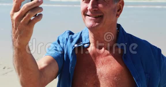 在海滩用手机打视频电话的老人视频的预览图