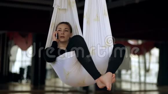 女运动员在飞行瑜伽课上休息时打电话视频的预览图