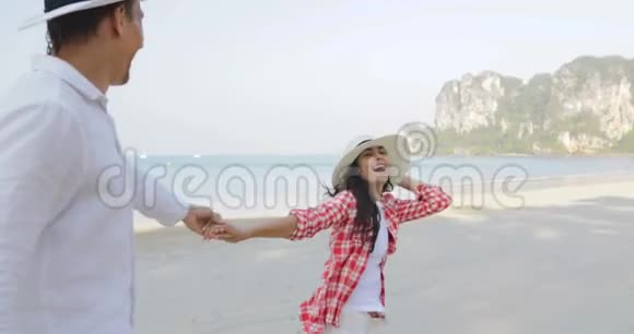 女人牵着男人的双手在沙滩上奔跑年轻的快乐游客在度假视频的预览图