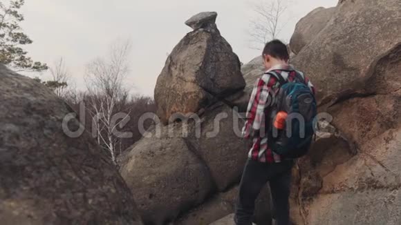 穿着格子衬衫的年轻人站在大岩石的顶部拍摄了几张令人惊叹的风景没有人视频的预览图