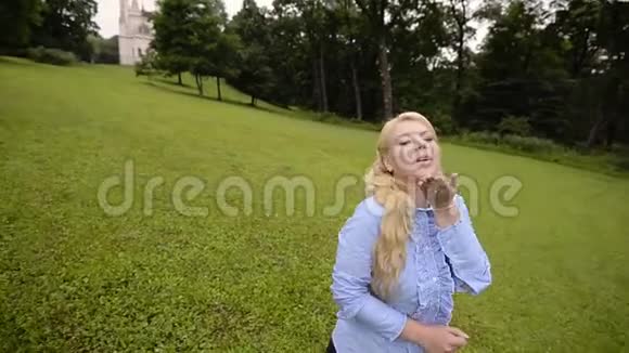 夏天在公园里摆姿势的年轻可爱的金发女孩视频的预览图
