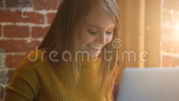 漂亮的女学生带着可爱的微笑在上网本笔记本电脑上键盘一些东西照明灯视频的预览图