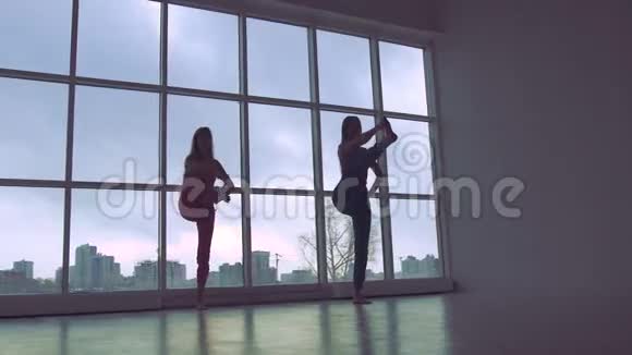 两个可爱的女人一起练习瑜伽姿势白色工作室与自然光视频的预览图