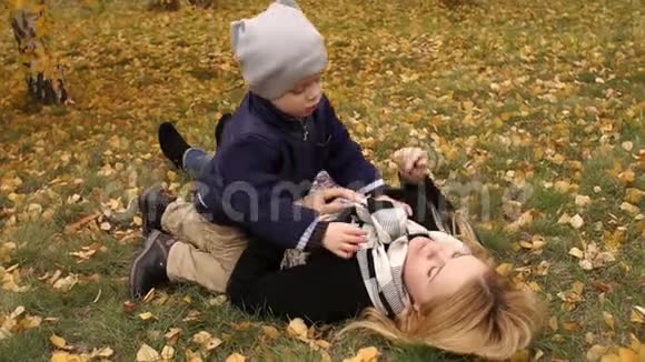 秋天公园里母子躺在黄叶上视频的预览图