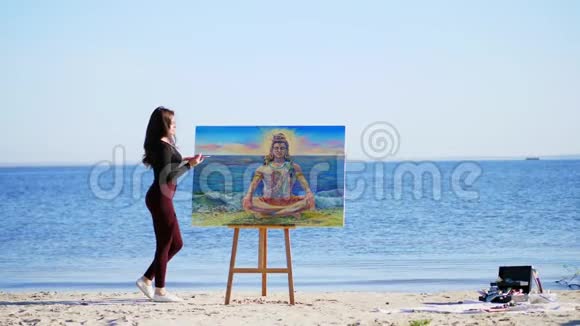夏天河边海滩上日出时一位穿着紧身西装的漂亮女艺术家画了一幅画湿婆神视频的预览图