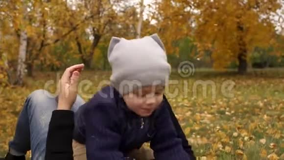 秋天公园里母子躺在黄叶上视频的预览图