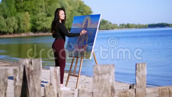 夏天河边海滩上日出时一位穿着紧身西装的漂亮女艺术家画了一幅画湿婆神视频的预览图