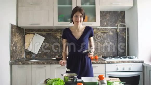 一个年轻微笑的女人在家厨房做饭时打开一个沙锅的画像视频的预览图